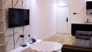 Un soggiorno moderno con una TV a schermo piatto, un tavolino rotondo e un divano.