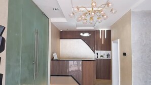 Un'accoglienza moderna con un mobile contenitore verde, un lampadario originale e un design murale strutturato.