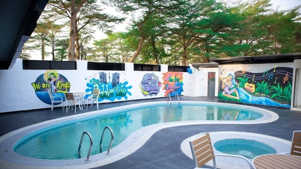 Una piscina all'aperto con un murale, lettini e un tavolino.