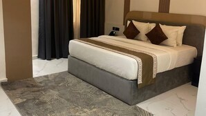 Una camera d'albergo moderna con un letto grande, un comodino, un condizionatore d'aria a parete e un tappeto decorato.