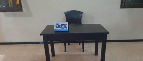 A room with a black table, a chair, and a window with metal bars.