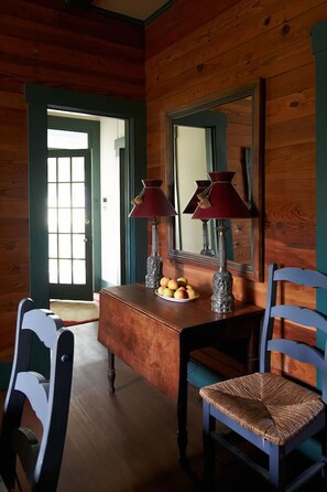 Un intérieur en bois avec un bureau en bois, deux chaises, un miroir et une porte dotée d’une fenêtre.