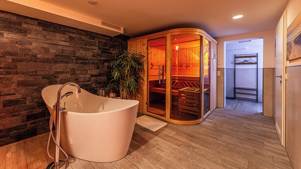 Een moderne badkamer met een vrijstaand bad, een houten wand en een houten sauna.