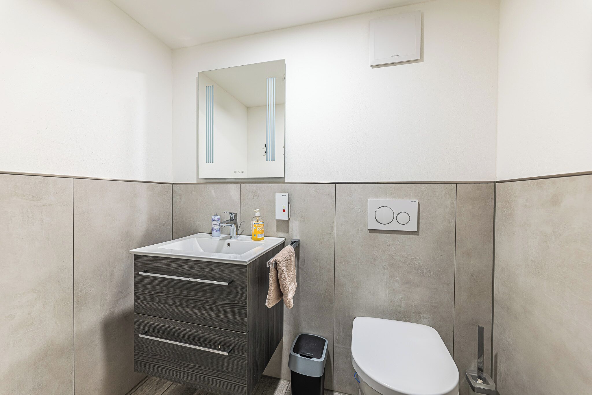 A modern bathroom with a sink, mirror, and toilet.