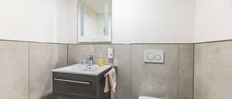 A modern bathroom with a sink, mirror, and toilet.