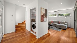 A modern living room with a sofa, a coffee table, and a washing machine in the corner.