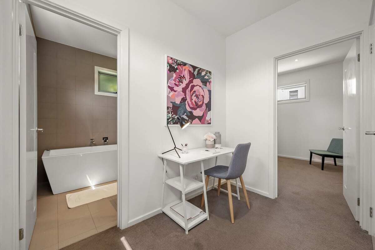 A room with a white desk, chair, and a large floral painting on the wall.