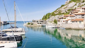 Ein Yachthafen mit vertäuten Booten, einer Steinmauer und Gebäuden mit roten Ziegeldächern.