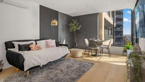 A modern bedroom with a bed, a desk, and a view of a cityscape. - Executive Designer Dreaming Home with All you need (Moonee Ponds)