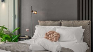 A modern bedroom with a bed, a bedside lamp, a potted plant, and a wall-mounted light fixture. - Executive Designer Dreaming Home with All you need (Moonee Ponds)