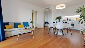 Ett modernt vardagsrum med en soffa, ett soffbord och en matplats.