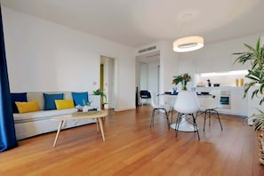 A modern living room with a sofa, coffee table, and dining area.