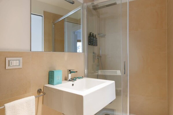 A bathroom with a white sink, a glass shower enclosure, and a mirror above the sink.