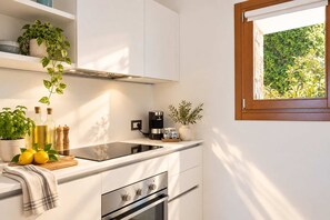 Eine moderne Küche mit Einbauherd, Kaffeemaschine und einem Fenster mit Blick auf Grünflächen.