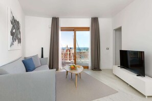 Ein modernes Wohnzimmer mit einer Couch, einem Couchtisch, einem Flachbildfernseher und einem Balkon mit Blick.