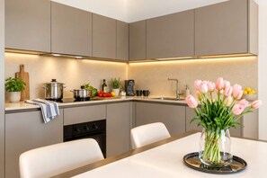 Cozinha moderna com ilha central, pia e área de jantar com um vaso de flores.