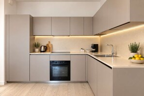 Cozinha moderna equipada com forno embutido, cafeteira e pia.