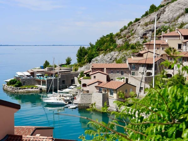 A coastal village with stone buildings, a marina, and boats.