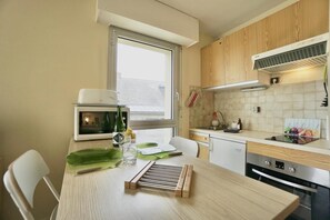 A modern kitchen with wooden cabinets, a built-in microwave, and a window providing natural light.