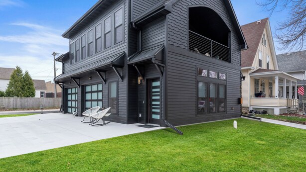 A two-story house with a dark exterior, large windows, and a covered front porch. - Downtown, Uniquely Designed, Near the Beach (Sheboygan)