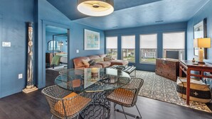 A modern living room with a glass coffee table, wicker chairs, a sofa, and a large window with blinds. - Downtown, Uniquely Designed, Near the Beach (Sheboygan)