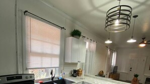 A modern kitchen with white cabinets, a stainless steel oven, a sink, and pendant lighting. - A perfect place in a perfect location (New Orleans)