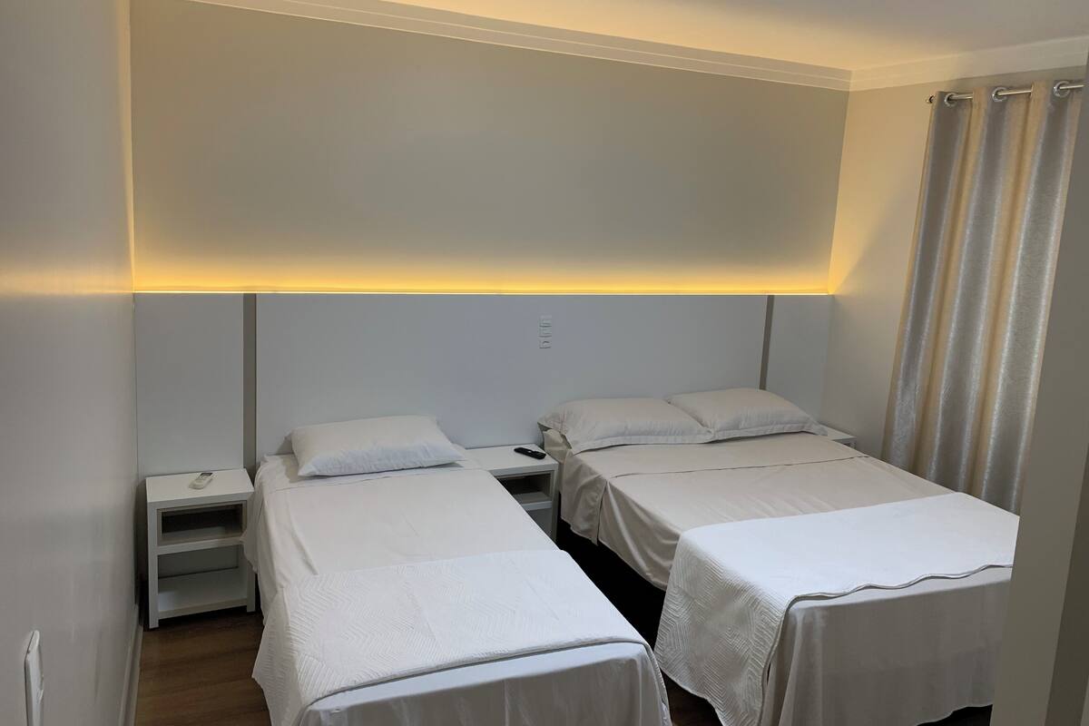 Ein Hotelzimmer mit zwei Einzelbetten, einem Nachttisch mit Telefon und einem Kopfteil mit integrierter Beleuchtung.