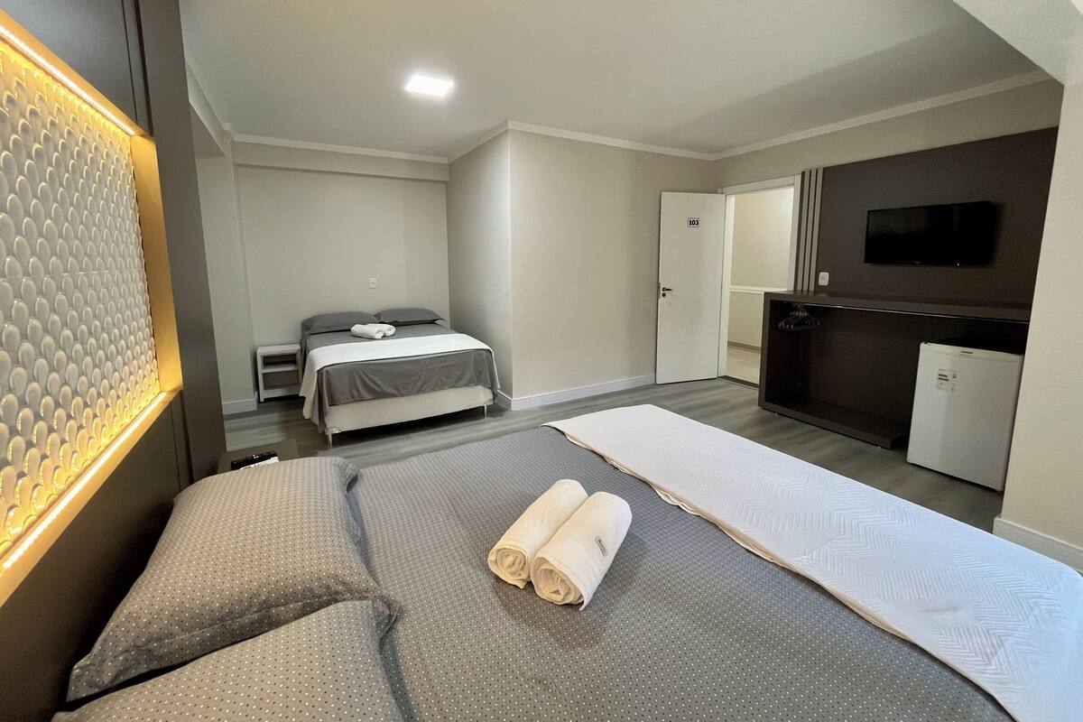Ein modernes Hotelzimmer mit Bett, Schreibtisch, Fernseher und Kühlschrank.