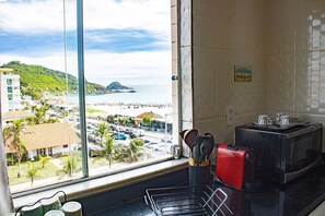 Cocina con vistas a la playa y al paisaje urbano, microondas y utensilios sobre la encimera.