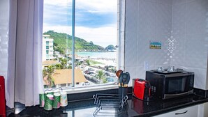 Cozinha com uma janela grande, micro-ondas e torradeira vermelha.