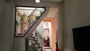 A staircase with a metal railing, leading to a landing with a white wall and a door. - Hotel O Homestay Kita Purworejo (Purworejo)