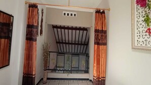 A room with a balcony, curtains, a decorative wall piece, and a potted plant. - Hotel O Homestay Kita Purworejo (Purworejo)