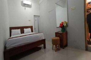 A bedroom with a bed, a wooden nightstand, a mirror, and a small stool. - Hotel O Homestay Kita Purworejo (Purworejo)