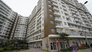 Un edificio residencial de varios pisos con balcones, un cartel de estacionamiento y un sendero para peatones.