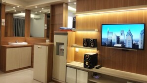 Un baño moderno con tocador, espejo y televisor montado en la pared mostrando una vista urbana.