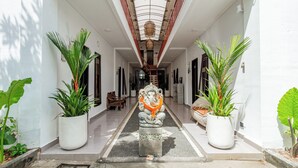 A corridor with a statue of a deity, potted plants, and a staircase leading to another level.