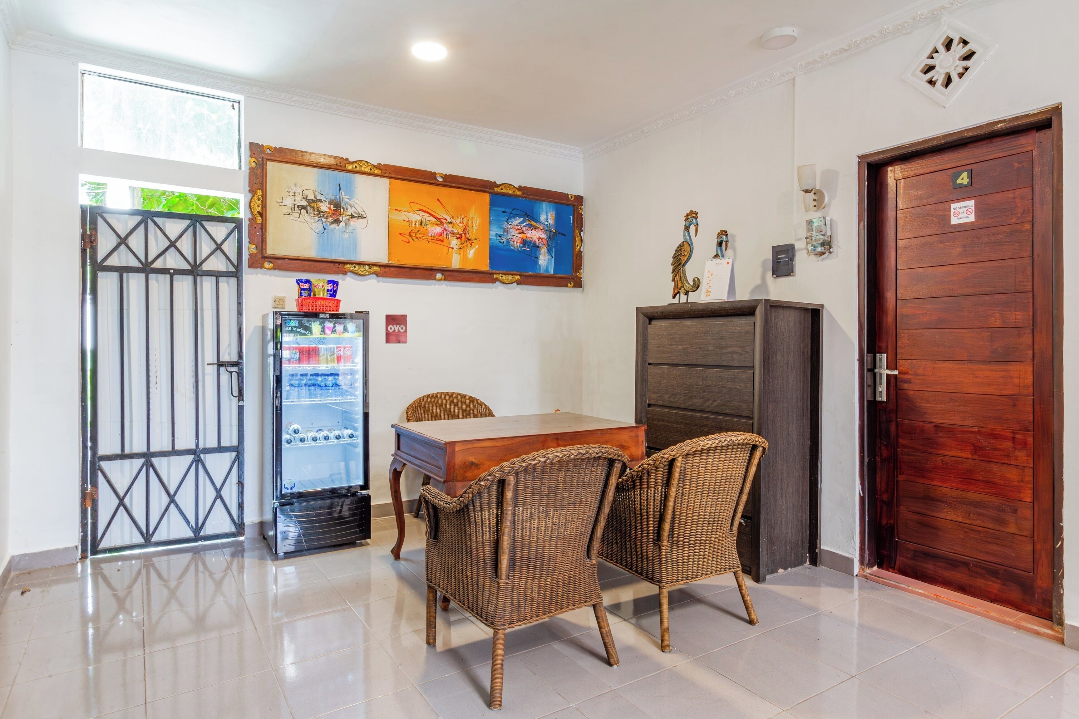 A dining area with a table, chairs, a refrigerator, and a door.