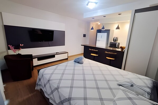 A modern bedroom with a bed, a TV mounted on the wall, a dresser, and a mirror.
