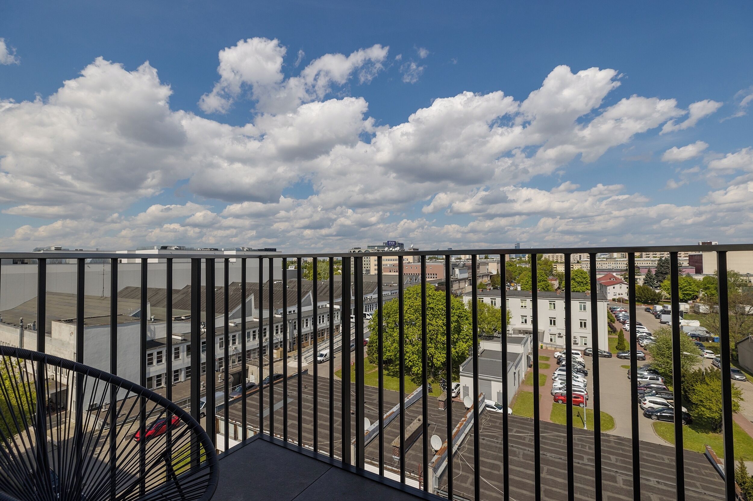A balcony with a view of a parking lot and buildings.