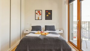 A modern bedroom with a large bed, two bedside tables, a window with a view, and two wall art pieces. - ShortStayPoland Zdziechowskiego B151 (Warsaw)