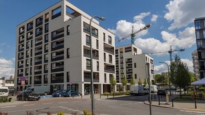 A modern multi-story building with balconies, a pedestrian walkway, and a construction crane in the background. - ShortStayPoland Zdziechowskiego B151 (Warsaw)