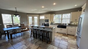 A spacious kitchen with a central island, ample counter space, and a dining area with a large table and chairs. - Lakefront Cabin, Bella Vista Lake Rayburn Dock, MTB and family friendly (Bella Vista)