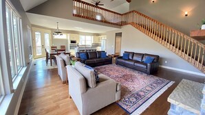 A spacious living room with a high ceiling, a wooden staircase, and a view of the kitchen and dining area. - Lakefront Cabin, Bella Vista Lake Rayburn Dock, MTB and family friendly (Bella Vista)