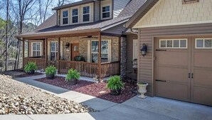 A two-story house with a covered porch, stone exterior, and a garage. - Lakefront Cabin, Bella Vista Lake Rayburn Dock, MTB and family friendly (Bella Vista)