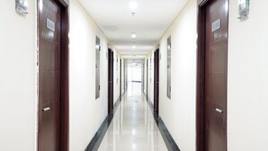 Un pasillo largo y estrecho con puertas a ambos lados, que conduce a habitaciones individuales.