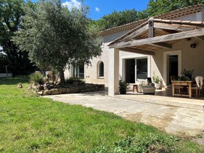 Relax under the shade of a pergola, surrounded by lush greenery and a serene lawn.