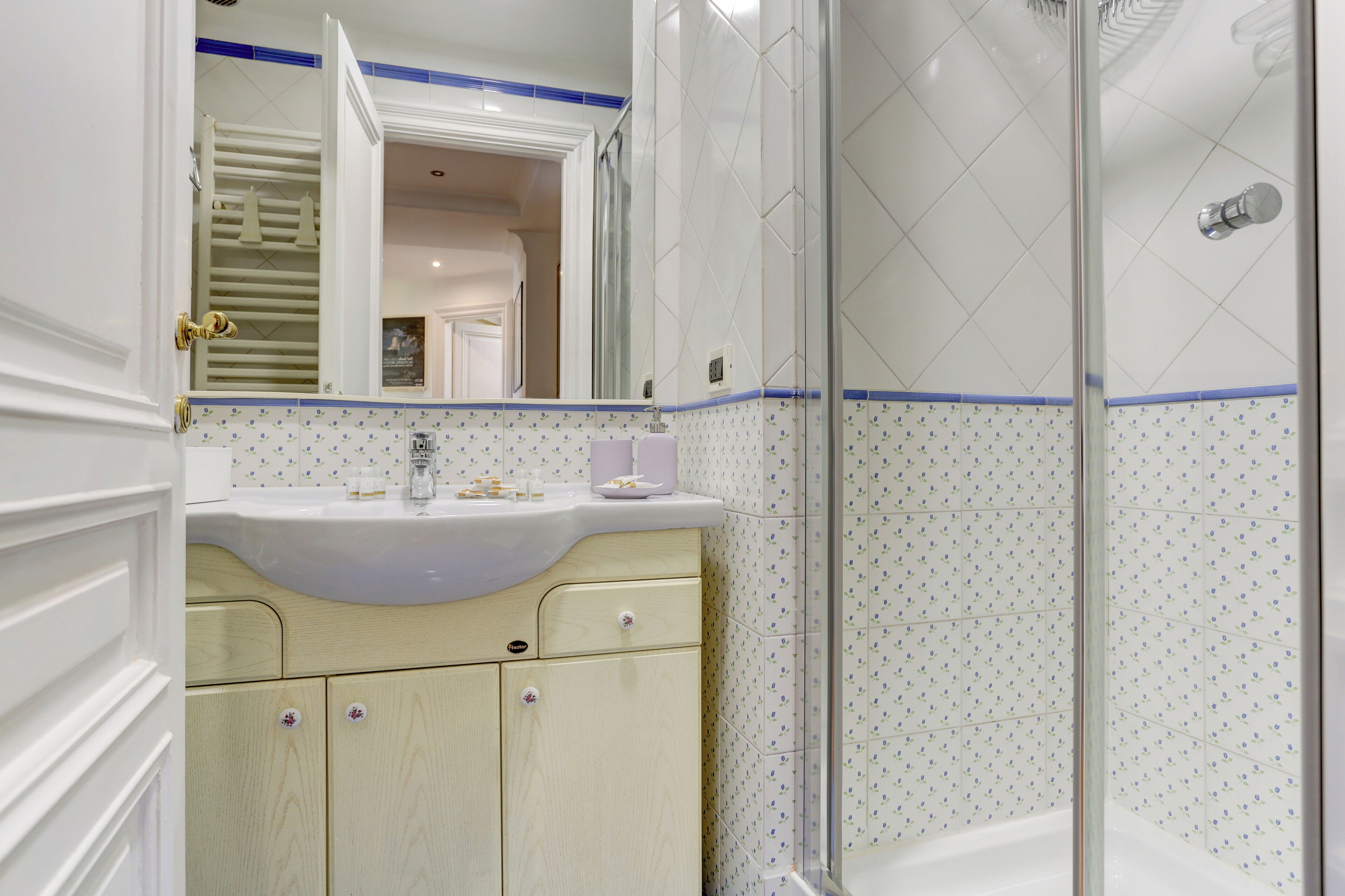 A bathroom with a white sink, beige cabinet, and a shower with a glass door.