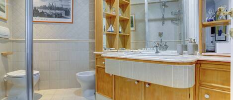 A modern bathroom with a large mirror, wooden cabinets, and a tiled floor.