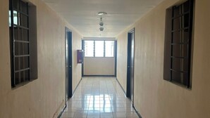 A corridor with tiled floors and walls, flanked by windows with metal bars. - OYO 93945 The Suite Metro Apartemen By Sa (Bandung)