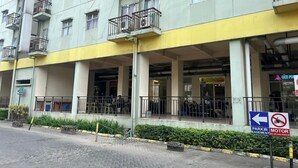A multi-story building with balconies, a covered entrance, and a sign indicating a motor vehicle parking area. - OYO 93945 The Suite Metro Apartemen By Sa (Bandung)